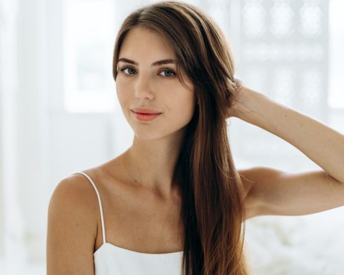 Portrait of adorable woman with healthy skin sitting in front of the camera with calm expression